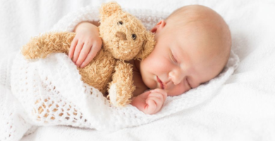 Un bebé durmiendo con un oso de peluche