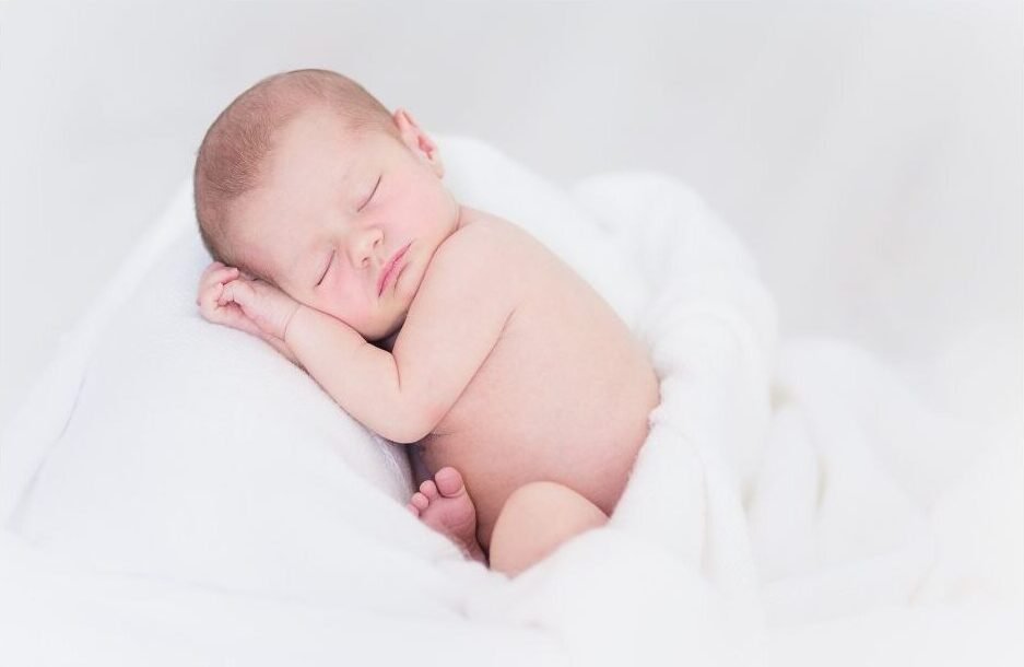 Un bebé durmiendo sobre una manta blanca